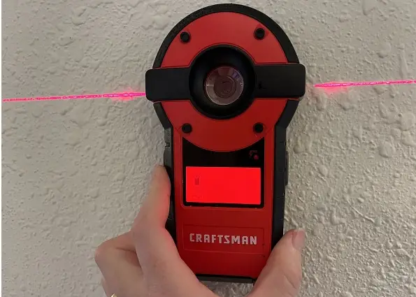A Craftsman stud finder being used on a textured wall